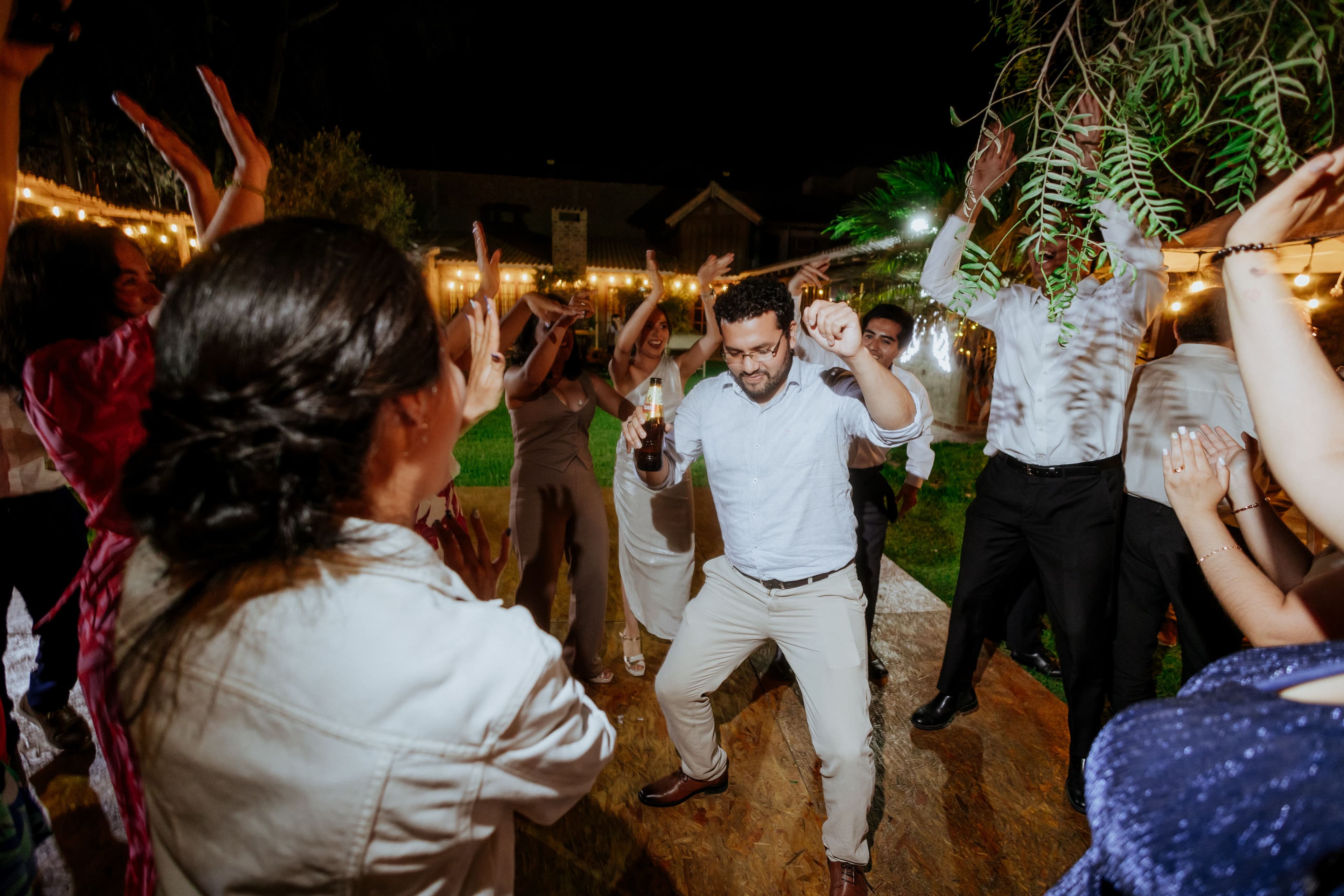 Wedding guests dancing energetically under string lights at night