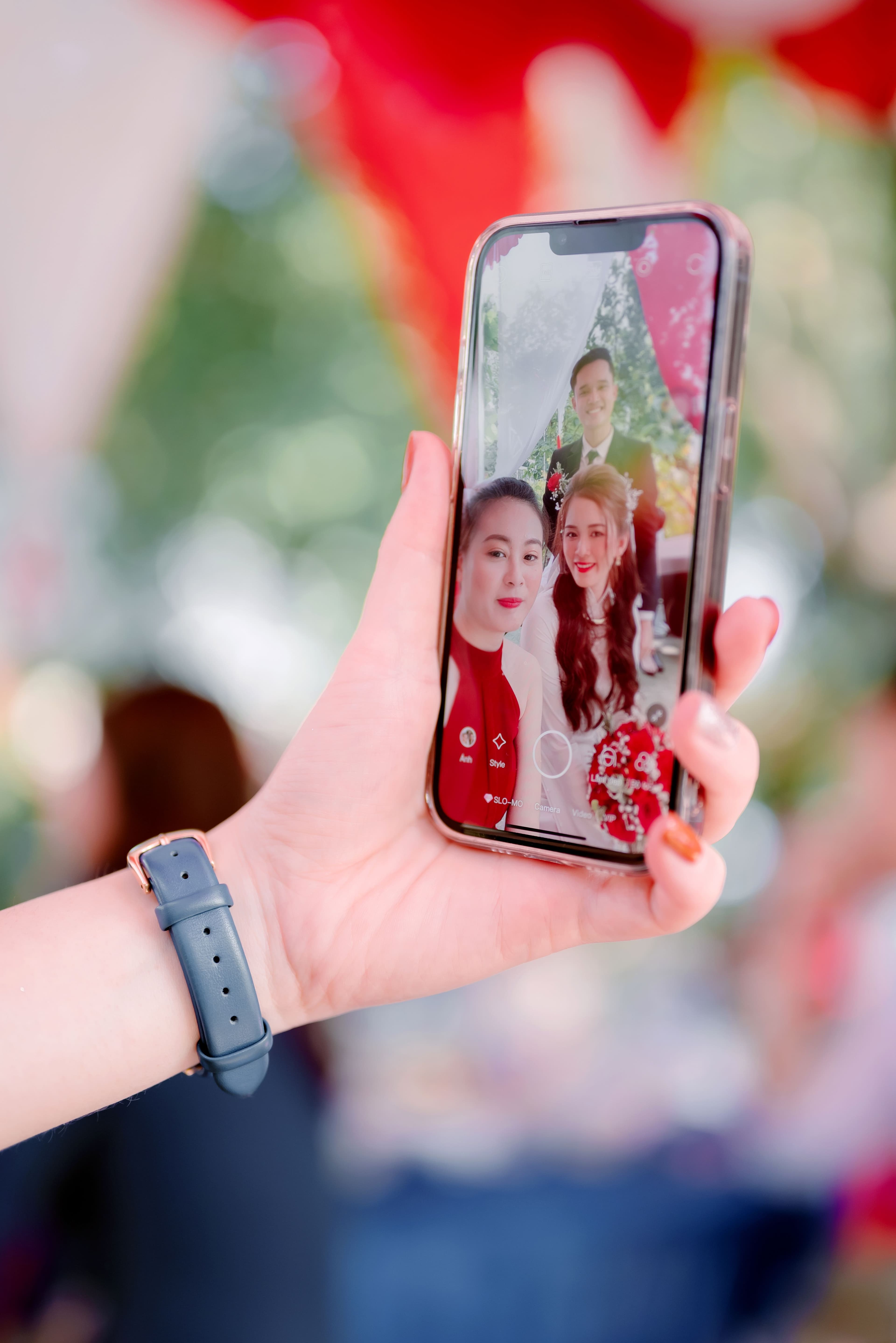 Mano sosteniendo un celular que muestra una selfie tomada durante la fiesta de boda