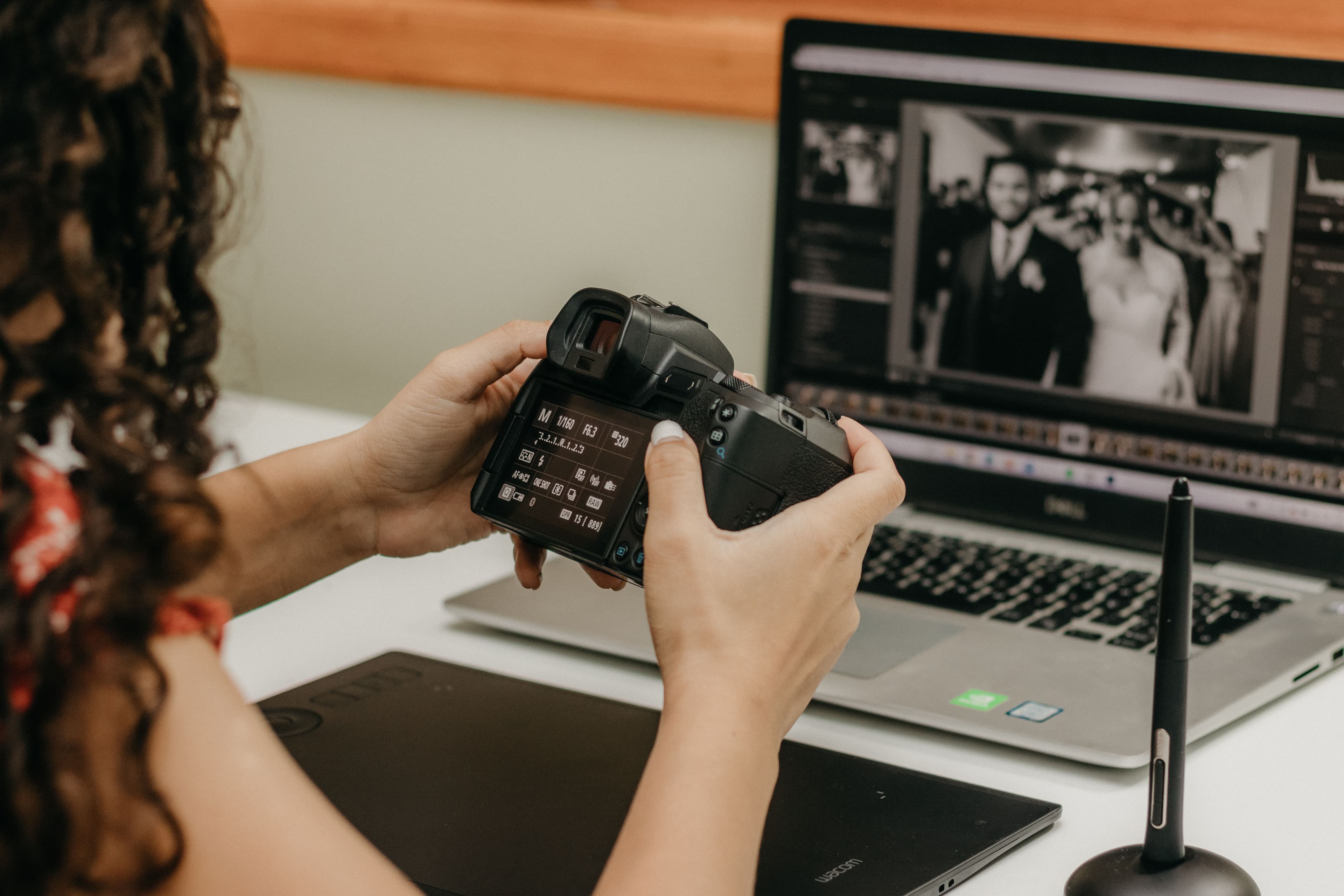 Fotografa che organizza foto di matrimonio su laptop e tavoletta grafica
