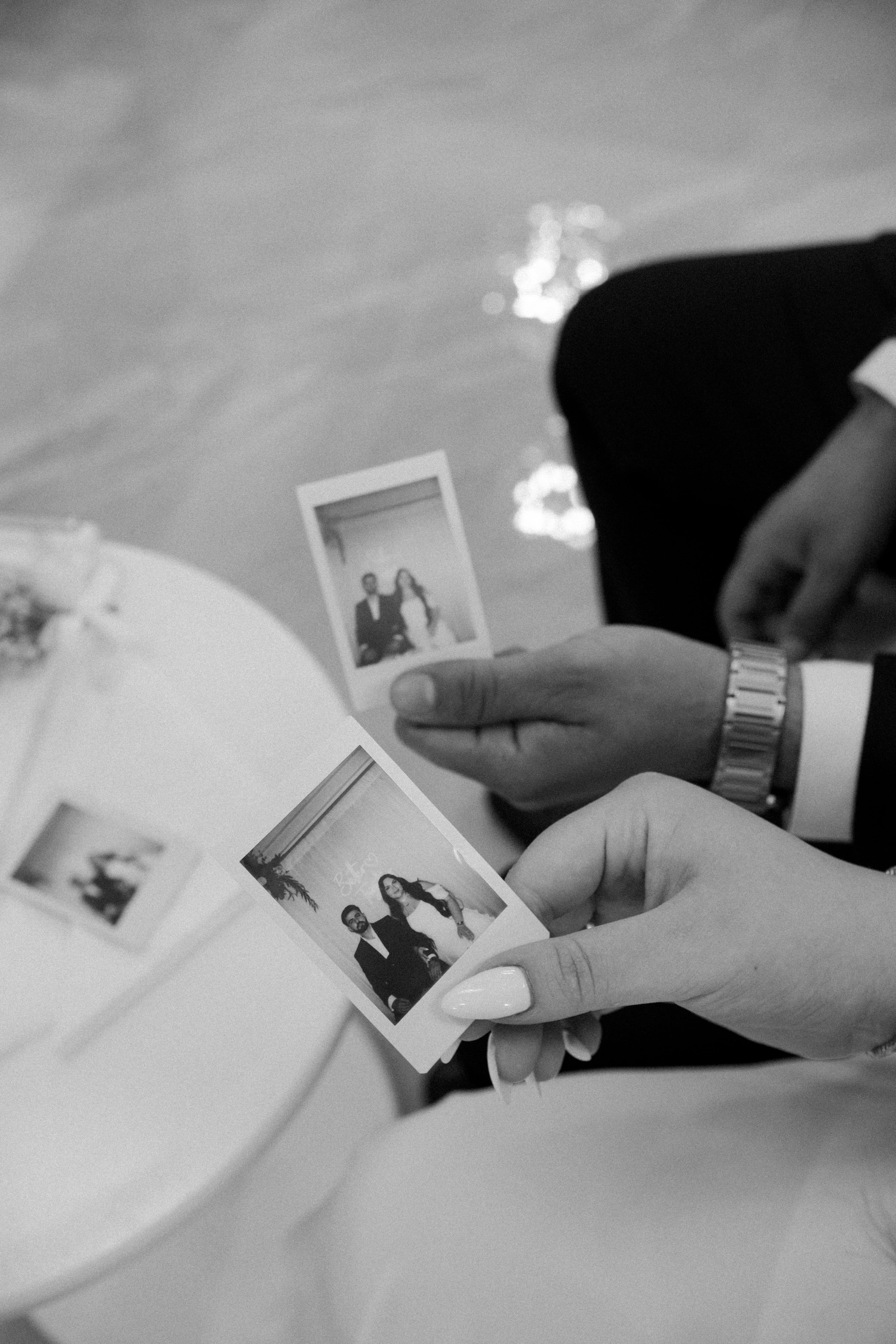 Couple sharing wedding polaroid photos at the party table